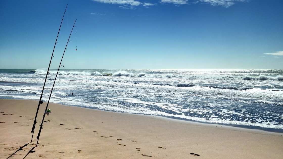 Surf fishing rods set up on an Australian beach with waves rolling in